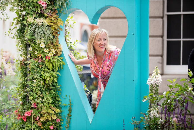 Helen leans through a turquoise heart structure